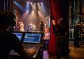 Régisseur lumière et techniciens en coulisses préparant un spectacle vivant sur scène sous les projecteurs d’un théâtre.