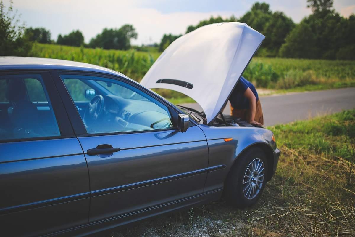 Une voiture avec le capot levé, un homme regarde le moteur