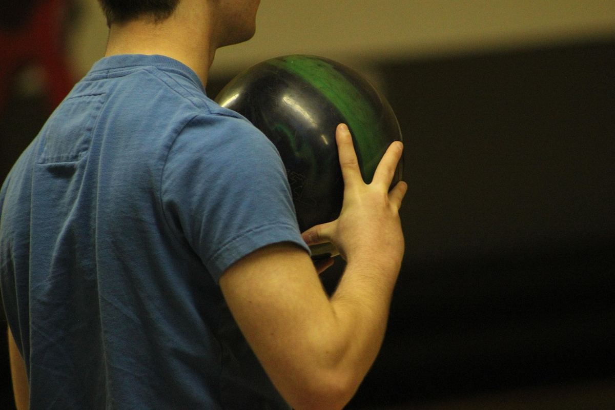 Un homme en t-shirt bleu prépare son lancer de boule de bowling