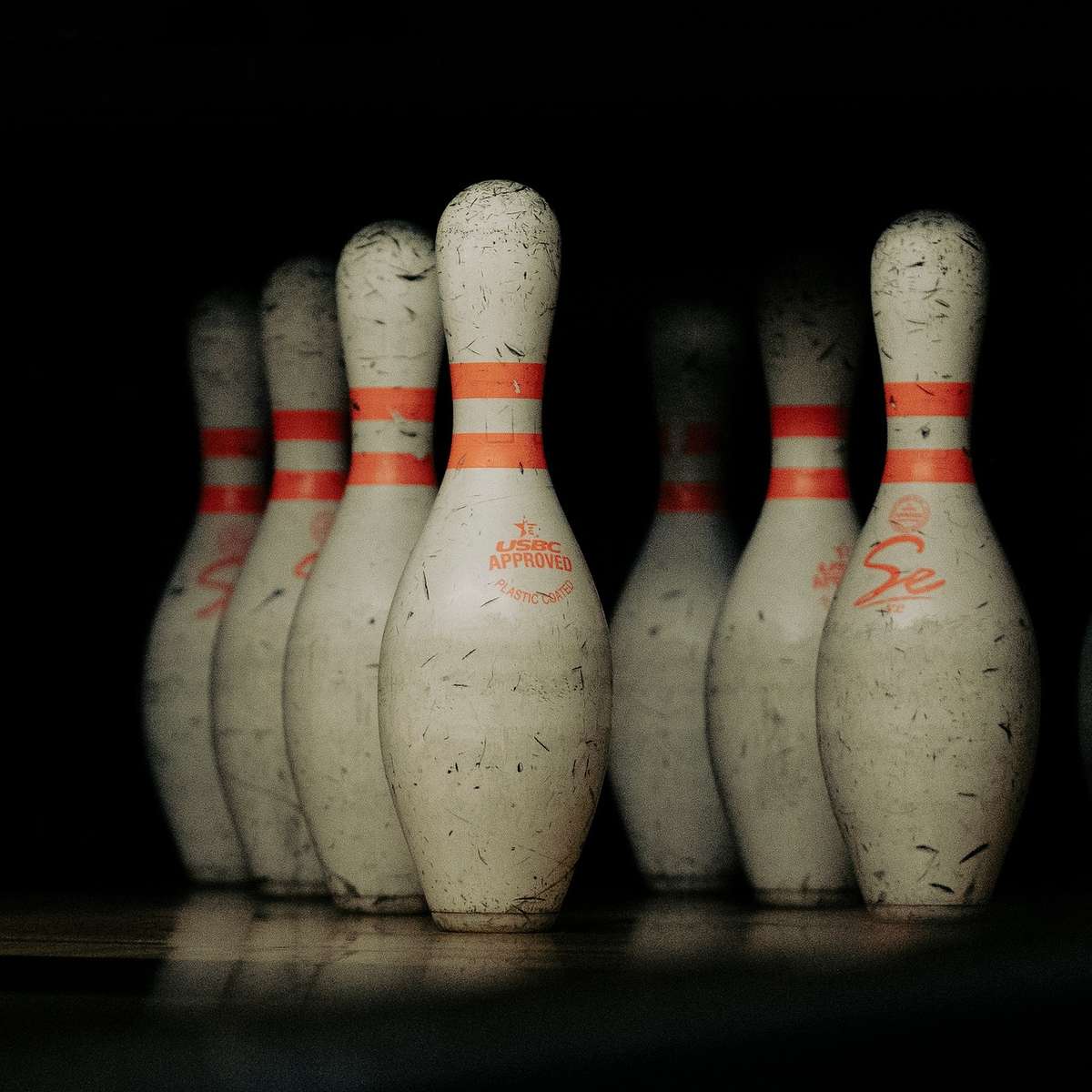 Pins de bowling blancs usés avec bandes orange, rangés en triangle