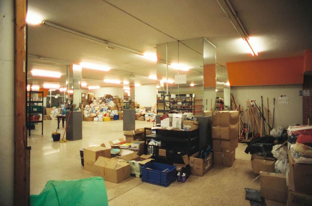 Un entrepôt rempli de caisses, palettes et matériel de tri
